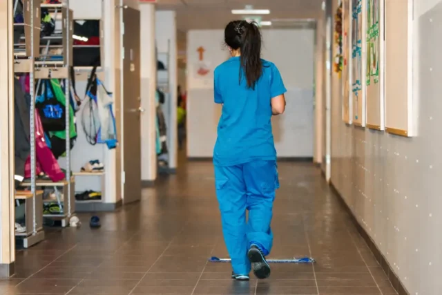 Eine Reinigungskraft bei der Reinigung eines Flurs in einer Schule